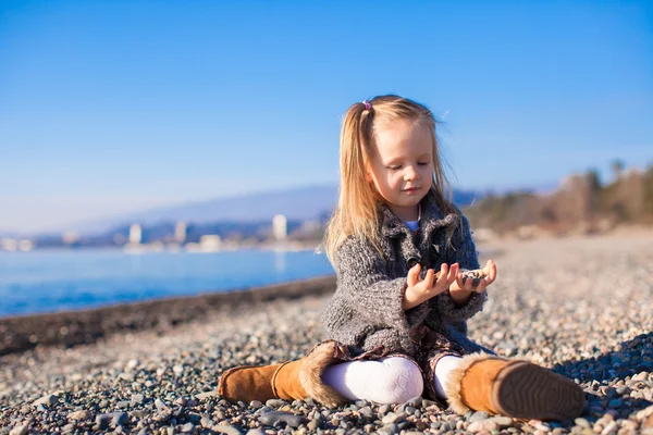 Adorable petite fille sur la plage dans un pull confortable et robe à la chaude journée d'hiver — Photo