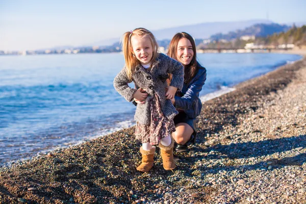 Bambina con mamma che si diverte in spiaggia in una giornata invernale — Foto Stock