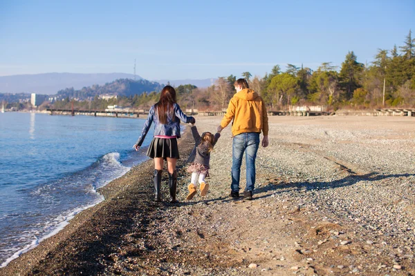 Οικογένεια τριών περπάτημα από τη μαύρη θάλασσα, στην ηλιόλουστη μέρα του χειμώνα — Φωτογραφία Αρχείου