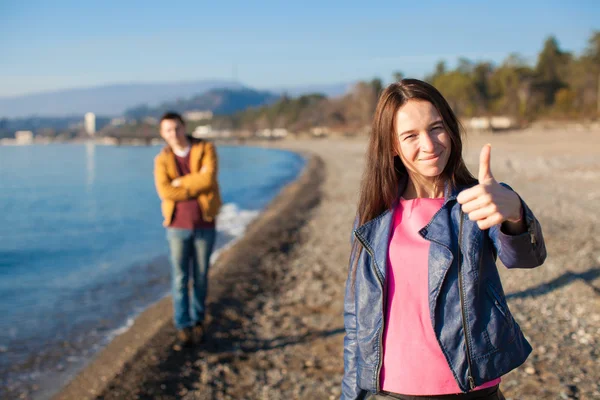 Nahaufnahme einer glücklichen Frau auf einem Hintergrund der junge Mann am leeren Strand — Stockfoto