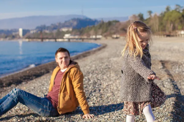 Adorable little girl with father having fun on beach in winter warm day — Stock Photo, Image