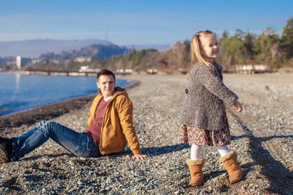 Liten flicka och unga far på stranden en solig vinterdag — Stockfoto