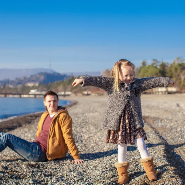 Adorable little girl with father having fun on beach in winter warm day — Stock Photo, Image