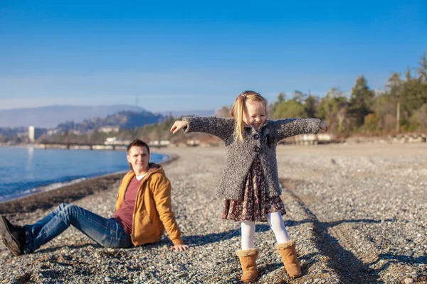 Bedårande liten flicka med far ha kul på stranden i vinter varm dag — Stockfoto