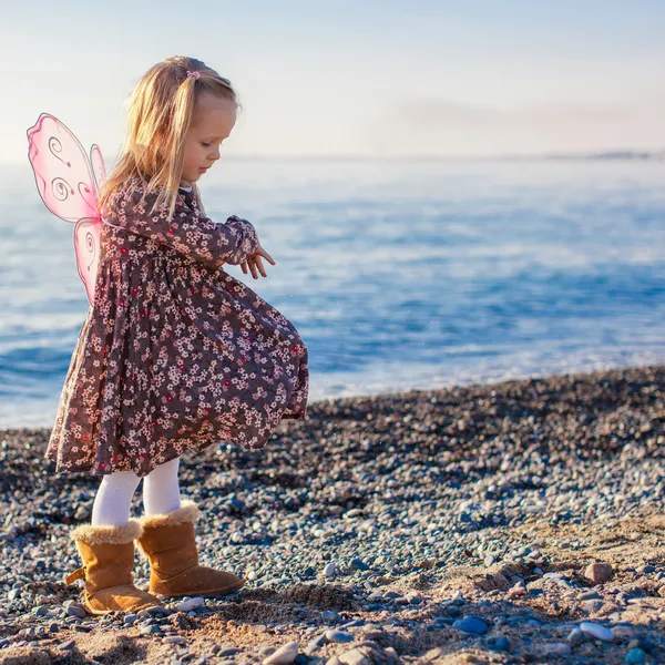 Entzückendes kleines Mädchen, das an einem sonnigen Wintertag Spaß am Strand hat — Stockfoto