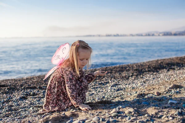 Adorável menina brincando na praia em um dia ensolarado de inverno — Fotografia de Stock