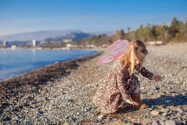 Entzückendes kleines Mädchen spielt an einem sonnigen Wintertag am Strand — Stockfoto