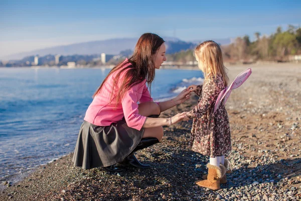 Meisje met moeder plezier op het strand in een winterdag — Stockfoto