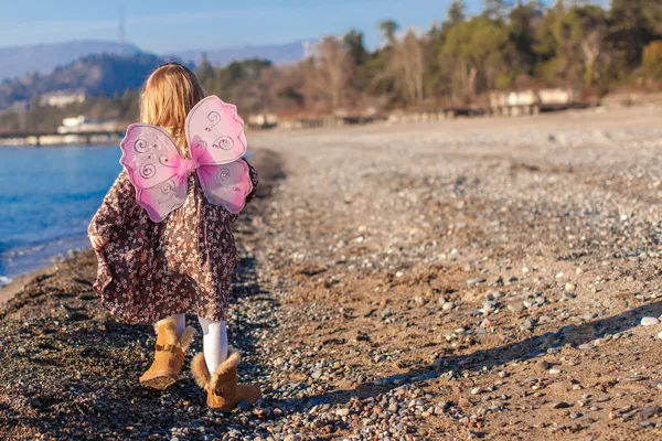 Attractive little girl on the beach in a suit with butterfly wings — Stock Photo, Image