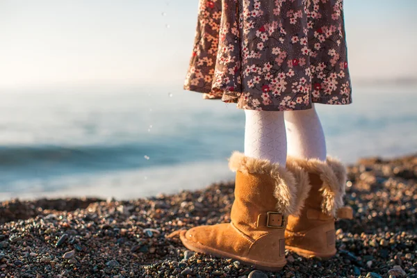 Close-up van benen meisje in gezellige bont laarzen achtergrond de zee — Stockfoto