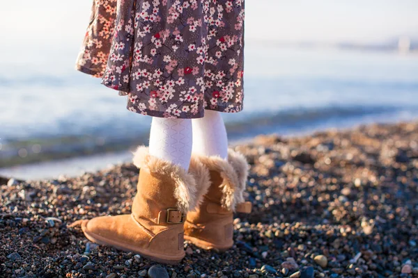 Primer plano de las piernas niña en botas de piel acogedora fondo el mar —  Fotos de Stock