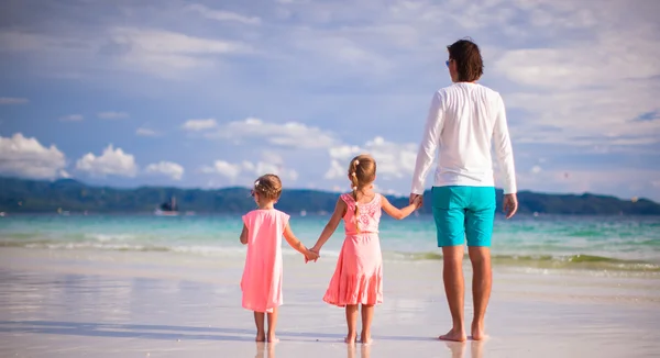 Back view of father and two girls walking on tropical white beach — Stock Photo, Image