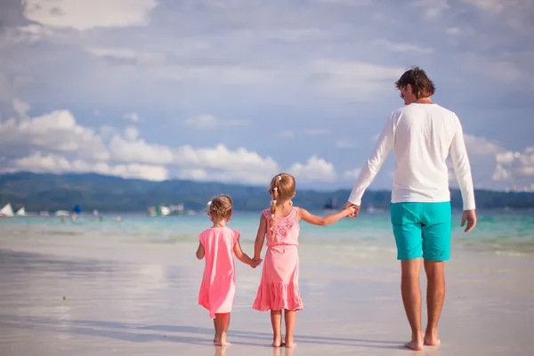 Vista trasera de dos niñas y padre joven en la playa tropical blanca — Foto de Stock