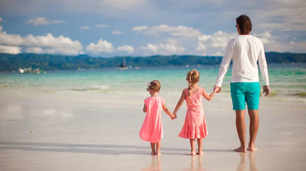 Vista trasera de dos niñas y padre joven en la playa tropical blanca — Foto de Stock