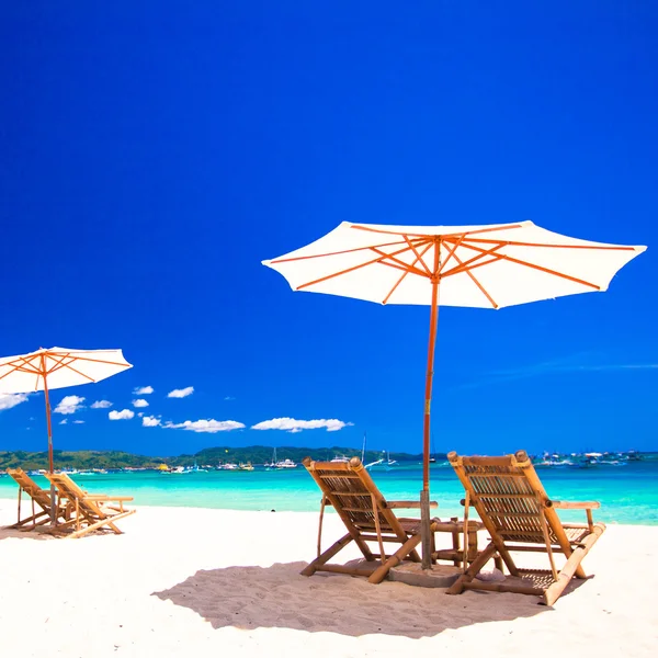 Wooden chairs and umbrellas on white sand beach facing the lagoon — Stock Photo, Image