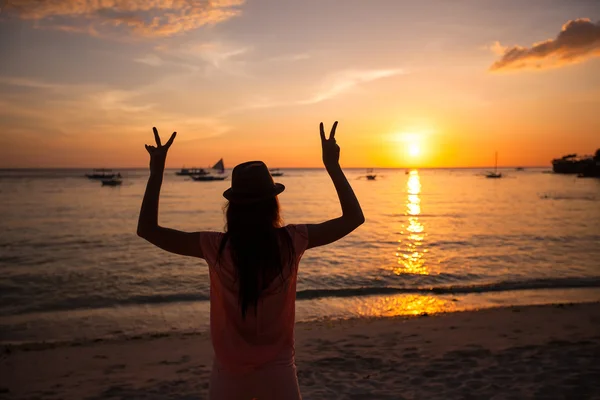 Silhouet van een jonge vrouw met opgeheven handen bij zonsondergang op het eiland boracay, Filippijnen — Stockfoto