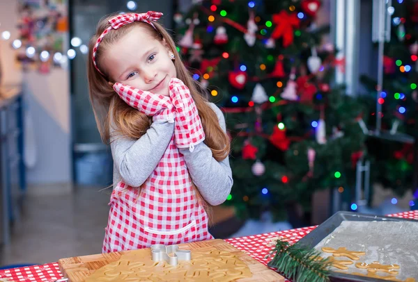 Entzückendes kleines Mädchen in Handschuhen beim Backen von weihnachtlichen Lebkuchen — Stockfoto