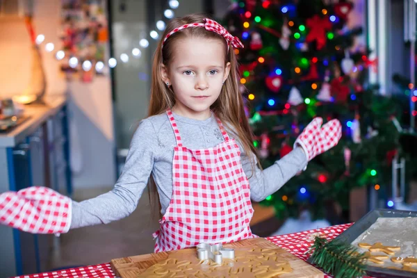 Fröhliches kleines Mädchen in Fäustlingen backt weihnachtliche Lebkuchen — Stockfoto