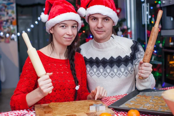 Familia feliz en los sombreros de Santa hornear galletas de jengibre de Navidad juntos —  Fotos de Stock