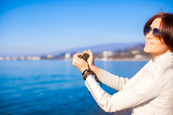 Woman hands holding small stones form heart shape background the sea — Stock Photo, Image
