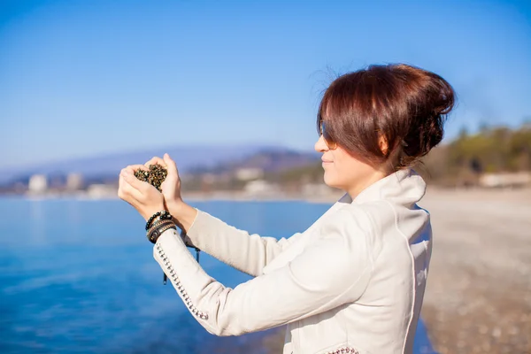 小さな石を持った女の手がハートの形をして海を背景に — ストック写真