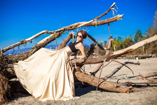 Encantadora joven con un vestido largo y hermoso posando en la playa —  Fotos de Stock