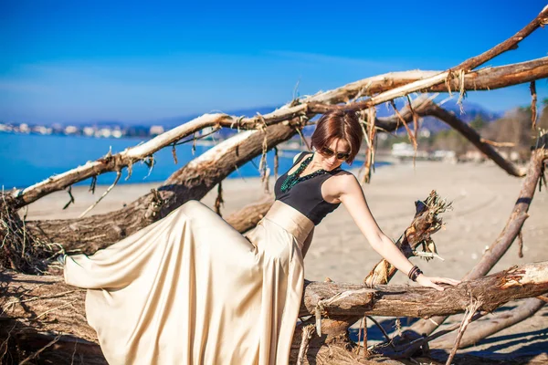 Encantadora joven con un vestido largo y hermoso posando en la playa —  Fotos de Stock