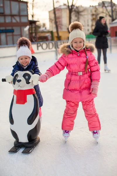Two adorable little girls skating at the ice-rink — Stock Photo, Image