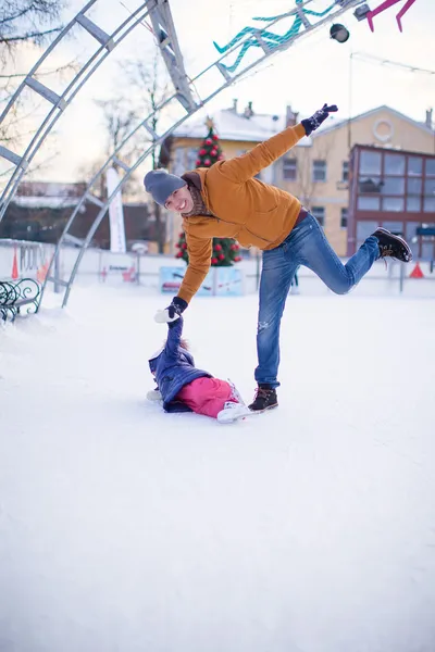 Young funny father and adorable little girl on a skating rink — Stock Photo, Image