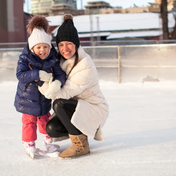 Leende ung mamma och hennes söta lilla dotter skridskoåkning tillsammans — Stockfoto