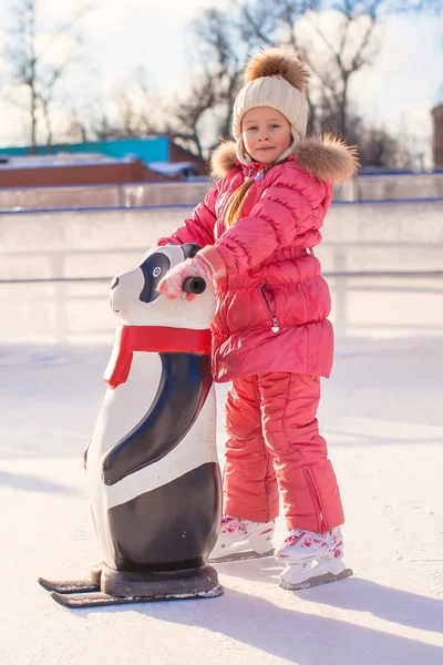 Kleines glückliches Mädchen lernt Eislaufen auf der Eisbahn — Stockfoto