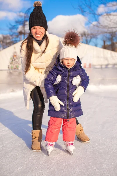 Счастливая очаровательная маленькая девочка и молодая мама учатся кататься на коньках — стоковое фото