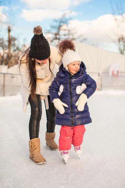 Ung mamma lära sin lilla dotter att åka skridskor på skridskobana — Stockfoto