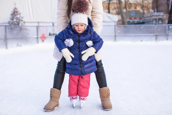 Glücklich liebenswertes kleines Mädchen und junge Mutter lernen Schlittschuhlaufen — Stockfoto