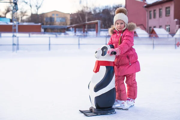 Little happy girl learning to skate on the rink — Stock Photo, Image