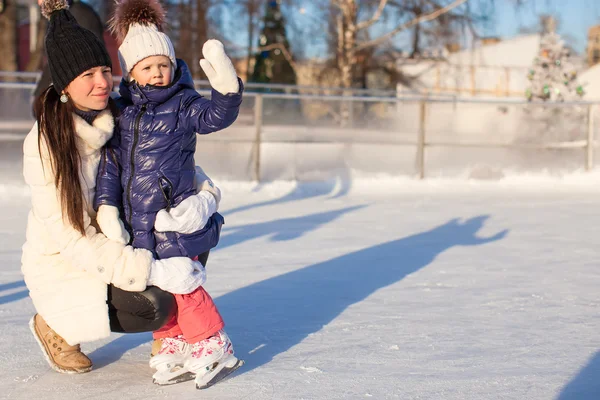 Joven madre y su linda hija pequeña en una pista de patinaje — Foto de Stock