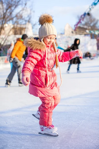 Charmig liten flicka har skridskor på ishallen- — Stockfoto