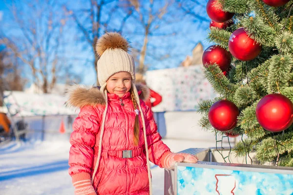 スケート リンク上にクリスマス ツリーの近く愛らしい少女の肖像画 — ストック写真