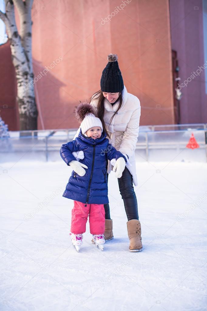 Little adorable girl with her mom learning to skate