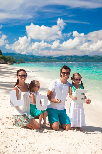 年轻幸福的家庭和两个孩子与热带度假爱字 — 图库照片