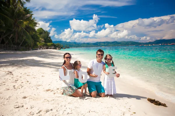 Famiglia giovane e due bambini con la parola AMORE in vacanza tropicale — Foto Stock