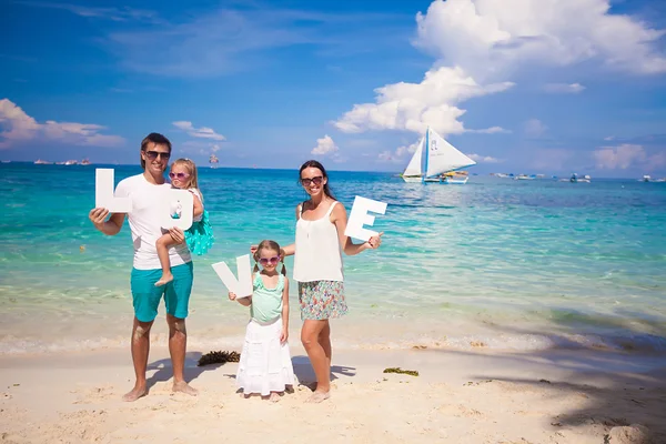 Giovane famiglia felice in vacanza tropicale con la parola AMORE — Foto Stock