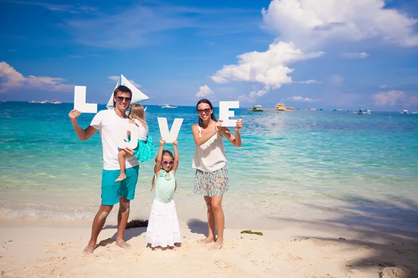 Młoda rodzina szczęśliwy na tropikalny wakacje z słowo miłość — Zdjęcie stockowe