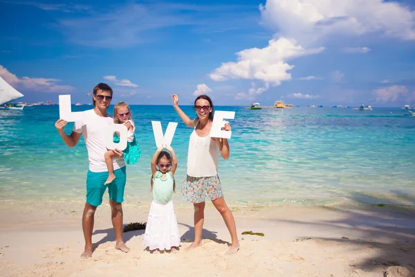 Familia joven y dos niños con la palabra AMOR en vacaciones tropicales — Foto de Stock