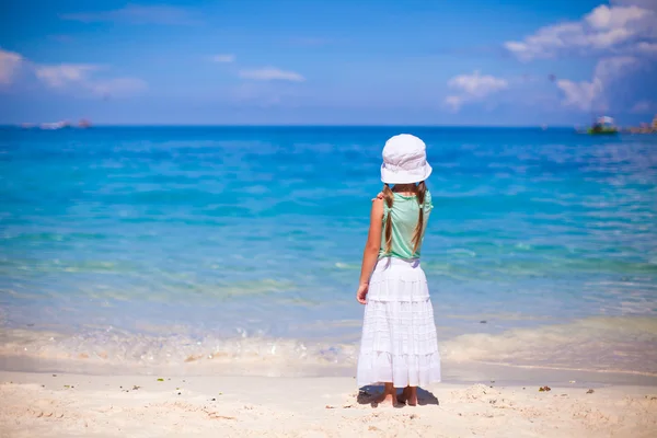 白い砂のビーチで海を見て帽子の少女の背面図 — ストック写真