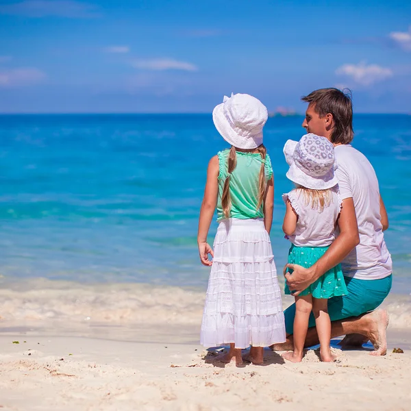 Vista trasera de niñas adorables y padre joven en la playa tropical blanca —  Fotos de Stock