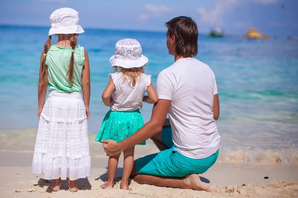 Vista trasera de niñas adorables y padre joven en la playa tropical blanca — Foto de Stock