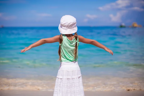 Achteraanzicht van een schattig klein meisje verspreiding haar armen op een exotische strand — Stockfoto