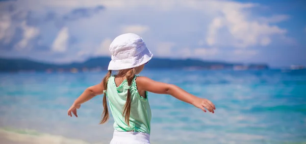 มุมมองด้านหลังของเด็กสาวสวยกระจายแขนของเธอบนชายหาดที่แปลกใหม่ — ภาพถ่ายสต็อก