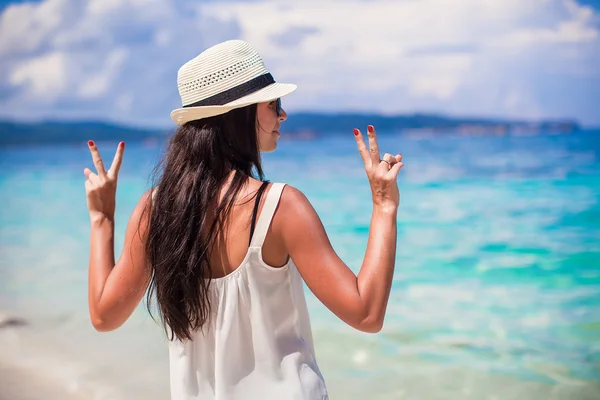 Jonge vrouw in hoed met opgeheven handen op perfecte strand — Stockfoto